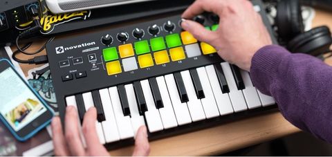 Colour photograph. One hand plays a keyboard and the other spins a knob on the interface above.