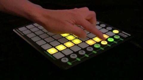 Colour photograph. A hand presses light-up buttons on a MIDI, which is a digital interface used to play or adjust sounds.