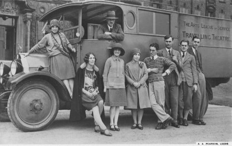 Postcard. Black and white photograph of four women and five men standing around or on a truck lettered with “The Arts League of Service Travelling Theatre”. The women wear drop-waisted skirts and the men high collared shirts with sweaters or vests.